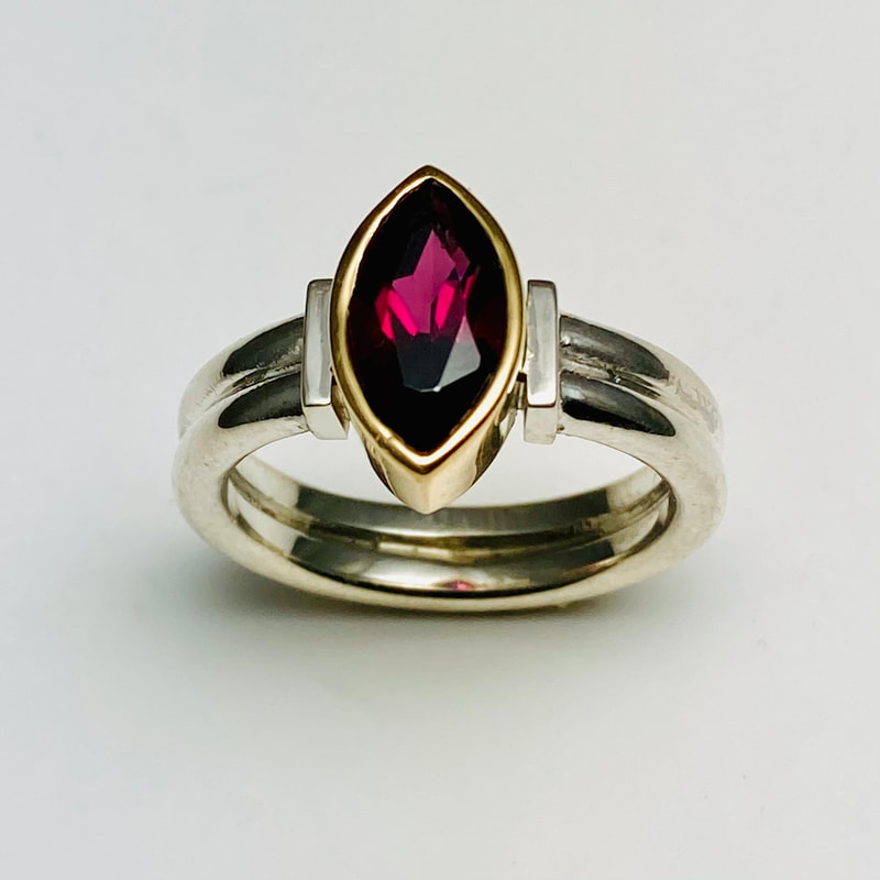 Sterling Silver Ring with one 18 Karat Yellow Gold bezel set marquise shaped Rhodolite Garnet.