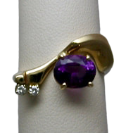 14 Karat Yellow Gold curved ring with an oval Amethyst and 2 smaller diamonds.